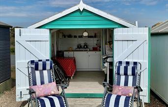 A view of the inside of a beach hut with chairs outside