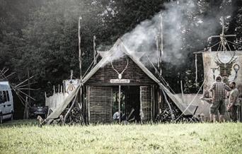 a rustic accommodation with woodfire smoke in a field with trees in the background