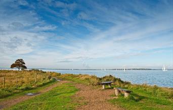 waterside walk with yachts in the distance on water.