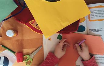 A child surrounded by bright cardboard at a craft table