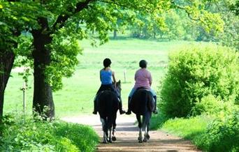 Two riders on horses walking down a country lane in Sussex
