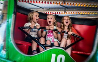 three children on a ride with happy but screaming faces