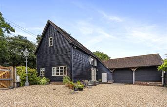 a barn building in dark wood with a gravel driveway