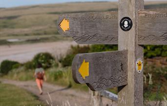 wooden trail signs and person walking in the background