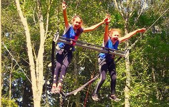 Two children with arms up in the air as they release the giant swing into free fall.