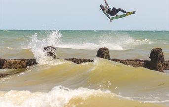 a kitesurfer in the air with waves