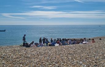 Group on the beach in the sunshine having a safety briefing before heading into the water