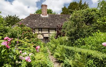 a garden in bloom with the priests house in the background