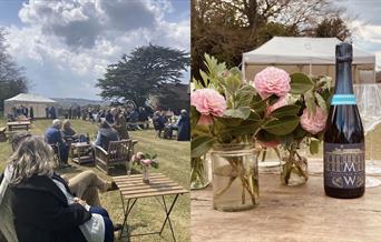 people sitting out side and a table with a bottle of wine and flowers on it