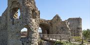 English Heritage Pevensey Castle entrance with wooden railings over stone bridge to castle walls