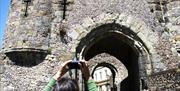 Lewes Castle entrance, visitor taking photo on mobile phone of the archways and cross-shaped windows