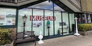 Outside a glass fronted image of Newhaven Museum showing images and objects against a pale green background