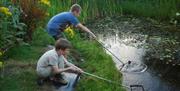 children with nets around a pond