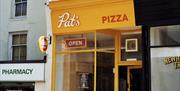 The front of Pat's Pizza's shop, it is yellow.