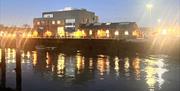 The Marine Workshops venue on Newhaven's riverside, lit up at night and reflected in the river.