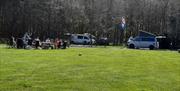 camper vans in the field with people sitting around in camping chairs