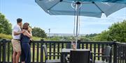 Couple enjoying a drink outside on the veranda of a glamping pod