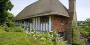 National Trust Alfriston Clergy House with thatched roof, high chimney stack and cottage garden