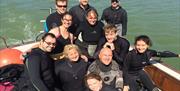 a group of people in diving suits sitting in a boat looking happy