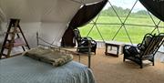 view from inside the glamping tent showing a bed and table and chairs by the window