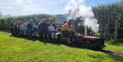 people riding a minature steam train