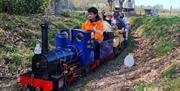 people riding a minature steam train