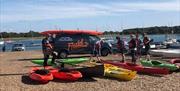 an instructor and students and kayaks and canoes on the shore at Itchenor