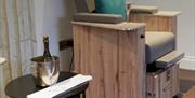treatment chair, with glass of bubbly and table with bottle and chiller set beside the chair