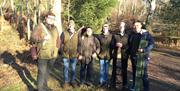 a group of men standing in some woods with their guns over their shoulders