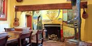 Farleys House, Chiddingly, Muddles Green, interior, fireplace, surrealist wall painting, hung painting and statute, with musical instruments hanging f