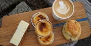 a spread of cake, cream tarts, a scone and a cappucino