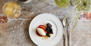 a plate of a dessert with blackberries, and a tart topped with icecream, served with a glass of wine