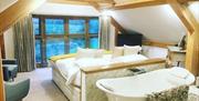 Large guest room with wooden beams and bath tub behind bed