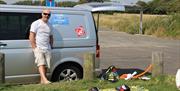 instructor standing by his van with a kiteboard on the grass