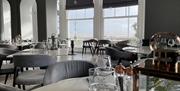 view of the tables with seafront through the window in the backgound