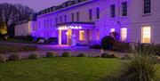 Exterior shot of Avisford Park Hotel with purple light