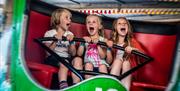 three children on a ride with happy but screaming faces