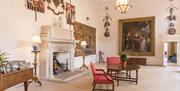 The Great Hall at Firle Place with fireplace and antique furniture on display