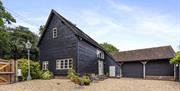 a barn building in dark wood with a gravel driveway