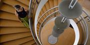 De La Warr Pavilion, Bexhill On Sea, interior image of spiral staircase  and a visitor holding the metal handrail.