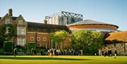 The exterior of the opera house, with guests milling around on a bright grassy area
