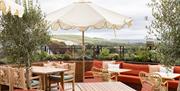 An outdoor terrace with tables and sofas with a view over the south downs
