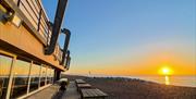 Perch on Lancing Beach building with a warm sunrise over the beach