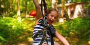 A child with arms outstretched at the end of a zipwire
