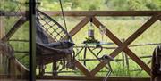 Swing chair on a secret terrace looking out over a meadow with a small table.