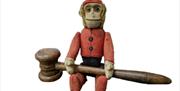 A picture of Henfield Museum's Victorian monkey vessel, holding a small wooden mallet used to play tuned shepherd's crooks.