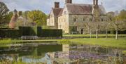 National Trust Bateman's House, pond in the foreground, surrounded by a bench, hedge and trees
