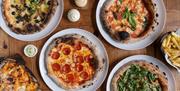 A selection of pizzas and dips on a board