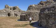 English Heritage Pevensey Castle with visitor on the pathway around the castle walls