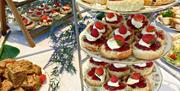 Tiered afternoon tea stand at Christina’s Tearoom filled with freshly baked homemade scones topped with strawberry jam, cream and fresh berries, surro